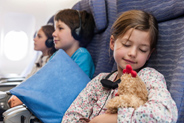 Girl sleeping on airplane holding stuffed toy